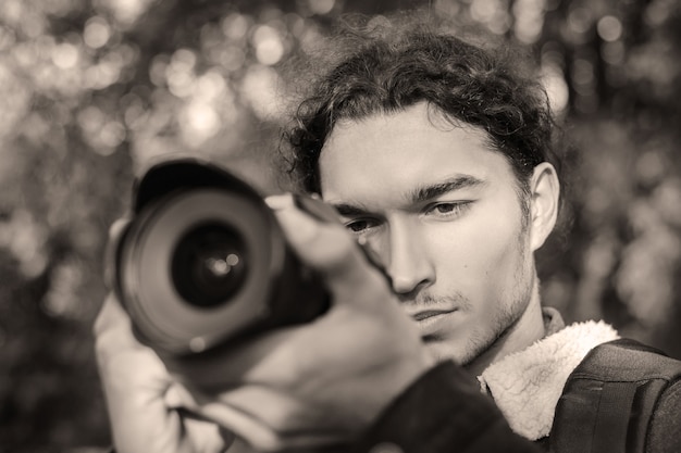 Black and white photo of photographer shooting someone in the park. Shooting photos in the park