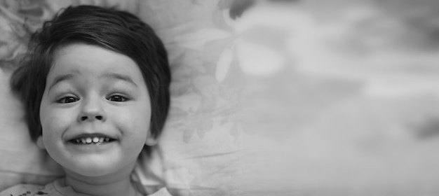 Black and white photo portrait of a young child lying on pillow