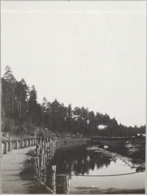 a black and white photo of a river with a bridge in the background