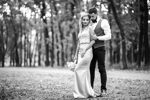 Black and white photo stylish couple of newlyweds posing on a bridge on wedding day.