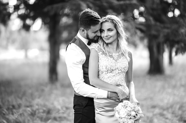 Black and white photo stylish couple of newlyweds posing on a bridge on wedding day.