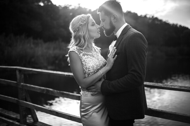 Black and white photo stylish couple of newlyweds posing on a bridge on wedding day.