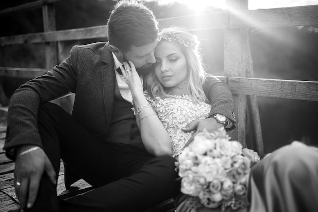 Black and white photo stylish couple of newlyweds posing on a bridge on wedding day