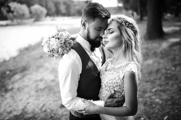 Black and white photo stylish couple of newlyweds posing on a bridge on wedding day