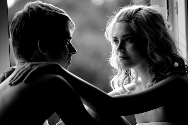 Black and white photo of a young couple in love hugging and looking romantically into the distance. Concept regarding love and romance and affection