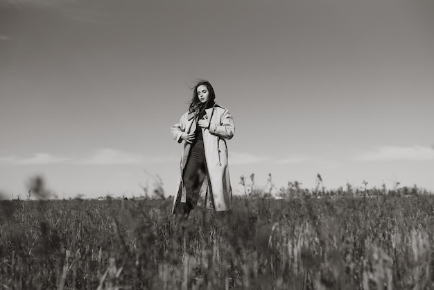 Black and white photo of Young woman stands in dry grass reeds field looking away Nature vacation