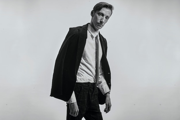 Fotografia in bianco e nero un uomo in abiti da ufficio su uno sfondo grigio ci guarda stancamente