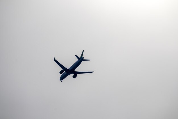 black and white picture with a silhouette of an airplane in a gray sky