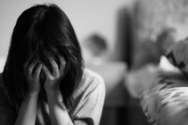 A black and white picture of a woman sitting with her hands\
over her face in despair women with depressive moods