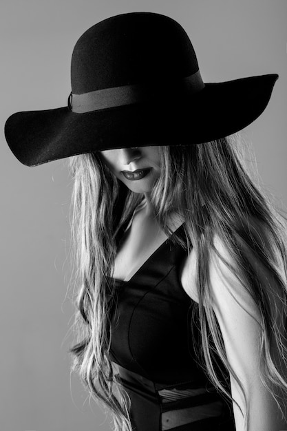 Черно-белый портрет красивой сексуальной женщины в черной шляпе
