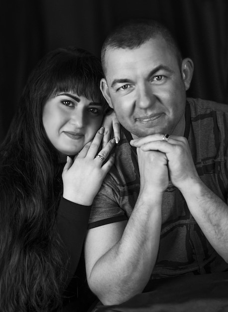 Black and white portrait of a couple in love in the studio when she lies on a mans shoulder