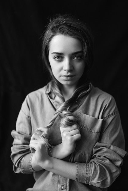 Black and white portrait of a dark haired beautiful young model over black background