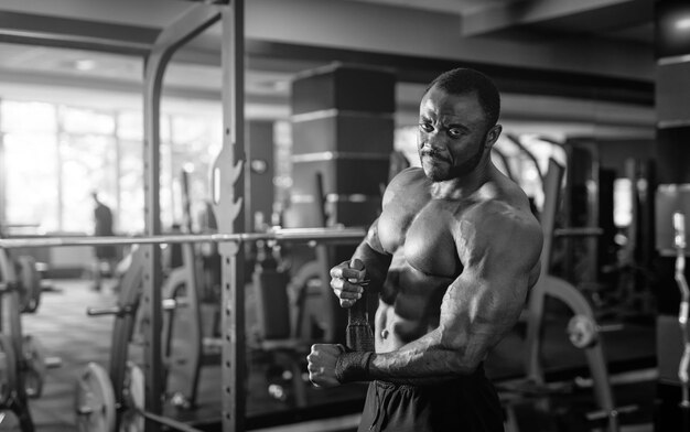 Black and white portrait of a muscular man without shirt after heavy workout Happy bodybuilder smiles to the camera