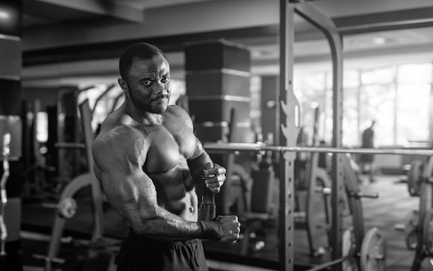 Black and white portrait of a muscular man without shirt after heavy workout Happy bodybuilder smiles to the camera