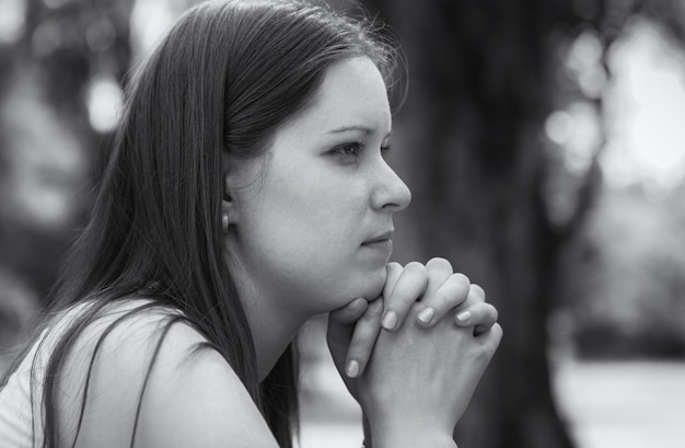 Black and white portrait in profile of a pensive sad and lonely young woman closeup Head of female person