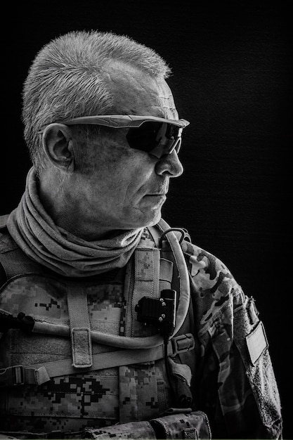 Black and white portrait of special forces white-haired veteran in field uniforms, black