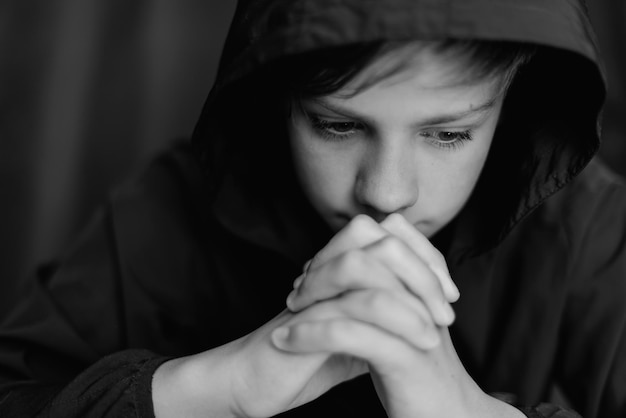 Black and white portrait of teenage boy on dark background Low key close up shot of a young teen boy Black and white photography Selective focus