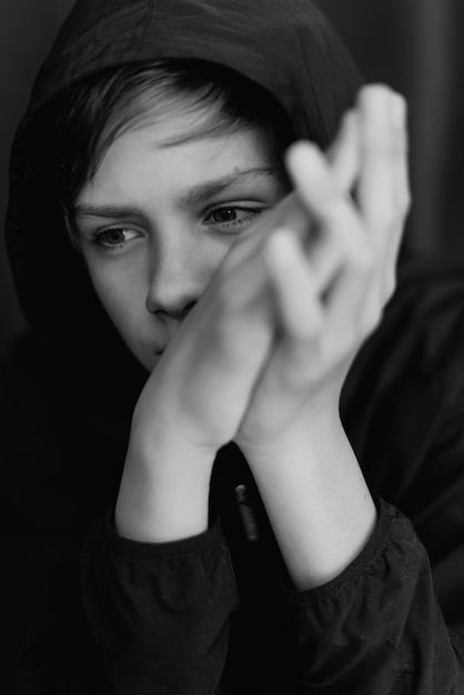 Black and white portrait of teenage boy on dark background Low key close up shot of a young teen boy Black and white photography Selective focus