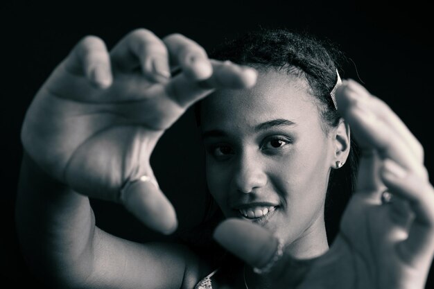 Photo black and white portrait of teenage girl making hand gestures at camera smiling and happy