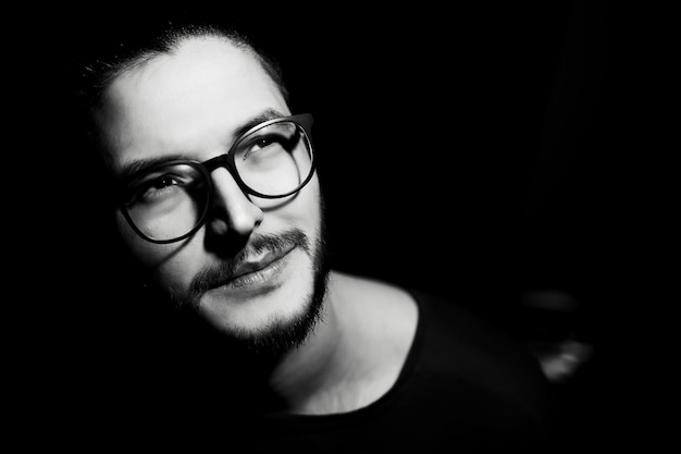 Black and white portrait of young man on dark background Closeup view