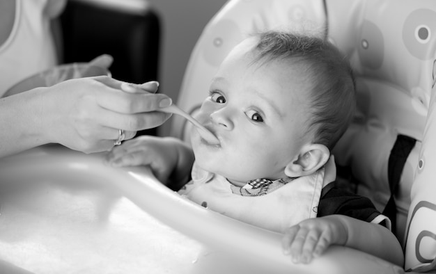 Black and white portrait of young mother feeding her baby