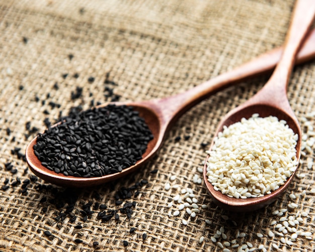 Black and white sesame seeds in a spoons on a textile surface