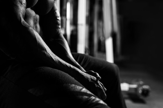 Black and white shot. Athlete sits on the simulator in the gym