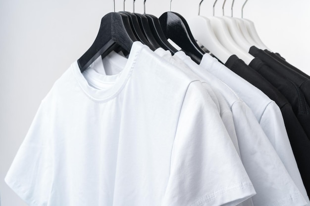 Photo black and white tshirts on hangers on metal rack isolated on white