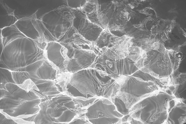 Black and white water surface with bright sun light reflections, water in swimming pool