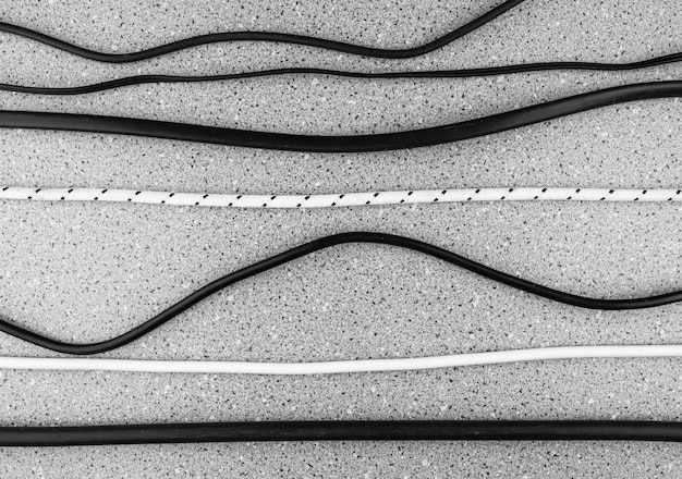 Black and white wires Assortment of electrical wires Various wires from gadgets chargers electrical goods Household wires cables cords