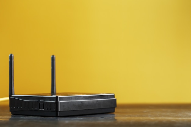 Photo black wi-fi router on a yellow background with free space.