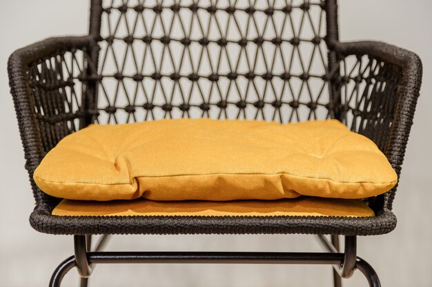 Photo black wicker chair with yellow pillows details