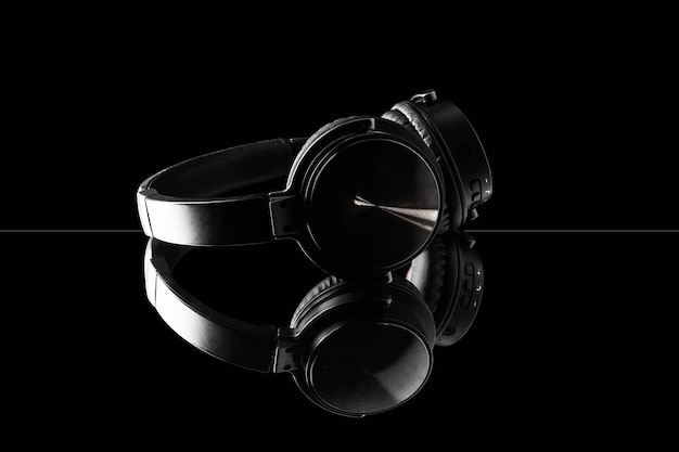 Black wireless headphones on dark reflective surface