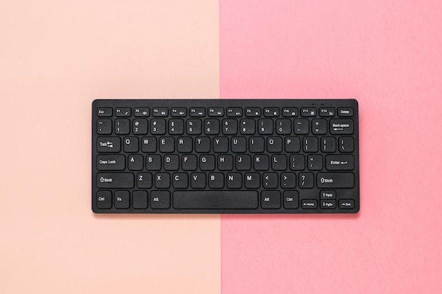 Black wireless keyboard on pink and red background Peripheral devices for computers