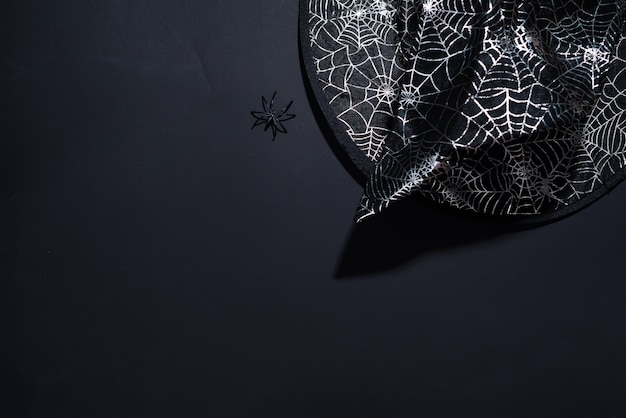 Black witch hat with a pattern of cobwebs on black background