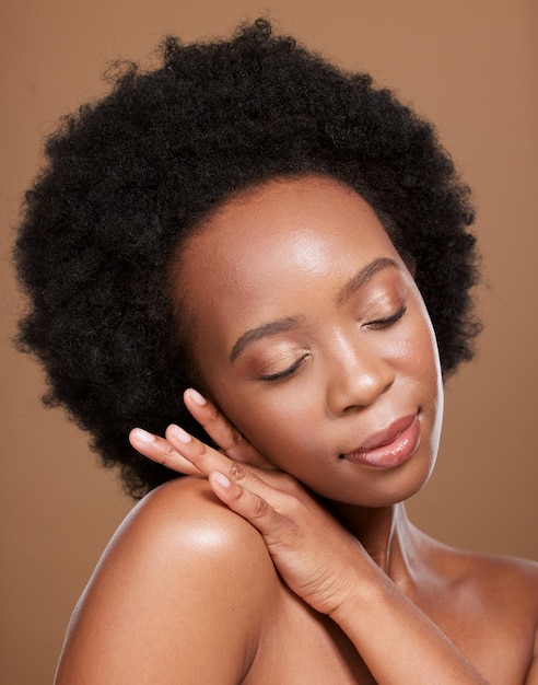 Black woman afro skincare and face with smile for cosmetics beauty or makeup against a brown studio background African American female relax in wellness for luxury facial hair or skin treatment