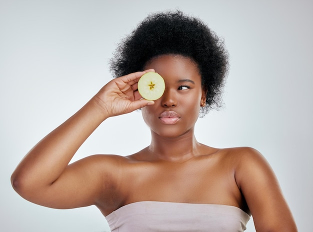 Black woman apple and afro for diet natural nutrition or health against a white studio background Face of African female person or model with organic fruit for fiber vitamins or skincare wellness