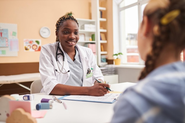 Black woman as pediatrician talking to child in clinic