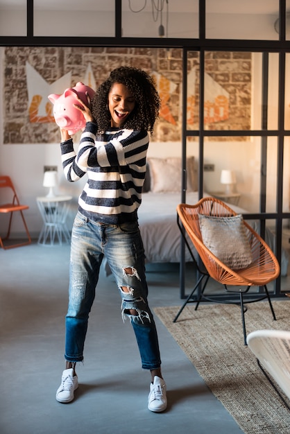 Photo black woman breaking her piggy bank