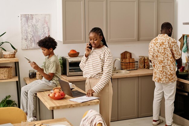 black woman calling coworker to discuss report when husband making lunch