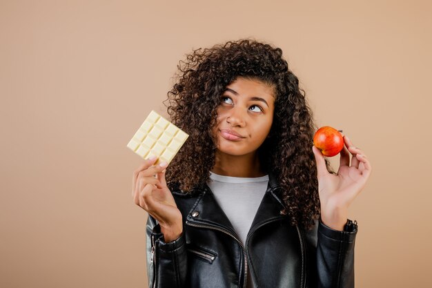 黒人女性は、リンゴとチョコレートを茶色の上で分離することを選択します