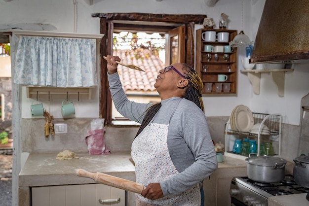 A black woman dances and sings happily and happily while cooking in a traditional vintage kitchen