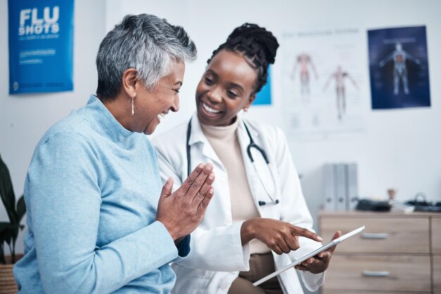 Photo black woman doctor and elderly patient with good news tablet and results for health advice and report happy african medic mobile touchscreen or healthcare with smile tech or support in hospital