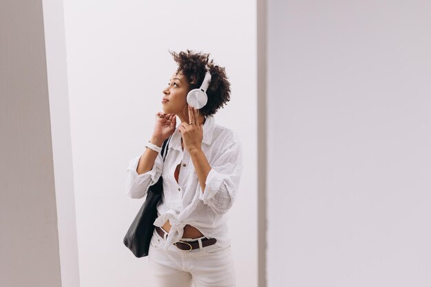 black woman dressed in white listening to music on headphones