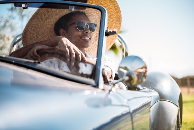 Black woman driving a vintage convertible car