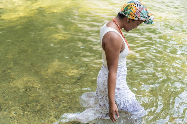 A black woman enters a river in the forest