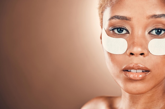 Black woman eyes and portrait for beauty patch on a mockup background for collagen dermatology Aesthetic model person in studio for skincare self care and facial skin glow with gel mask space