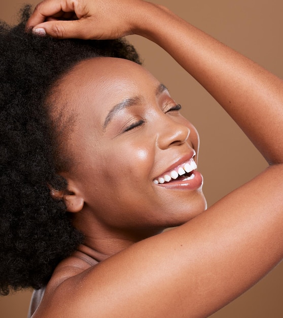 Black woman face and smile for skincare cosmetics makeup of luxury treatment against brown studio background African American female relax smiling in satisfaction for facial care and perfect skin