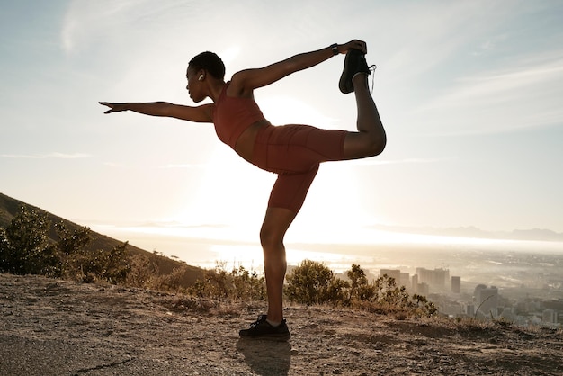 Black woman fitness and stretching on mountain for exercise cardio workout or balance in the outdoors African American woman in warm up yoga stretch during sunset for healthy lifestyle in nature