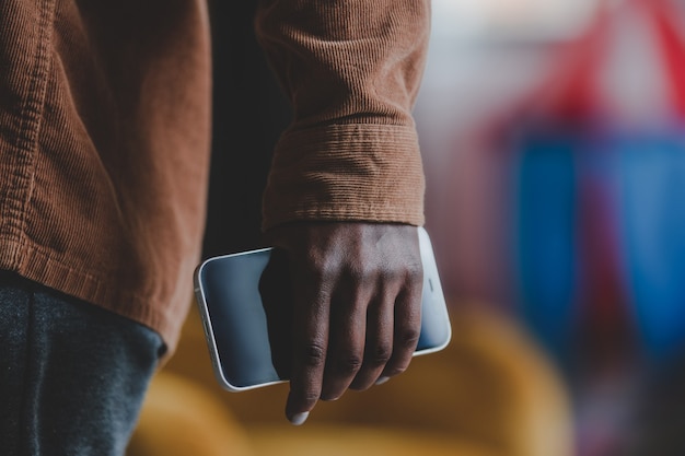 Black woman hand holding smartphone indoor